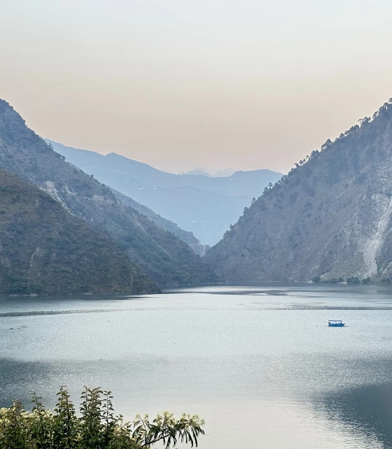 Chamera Lake near Dalhousie, Himachal Pradesh, surrounded by Himalayan mountains and tranquil waters with a boat sailing across the lake.